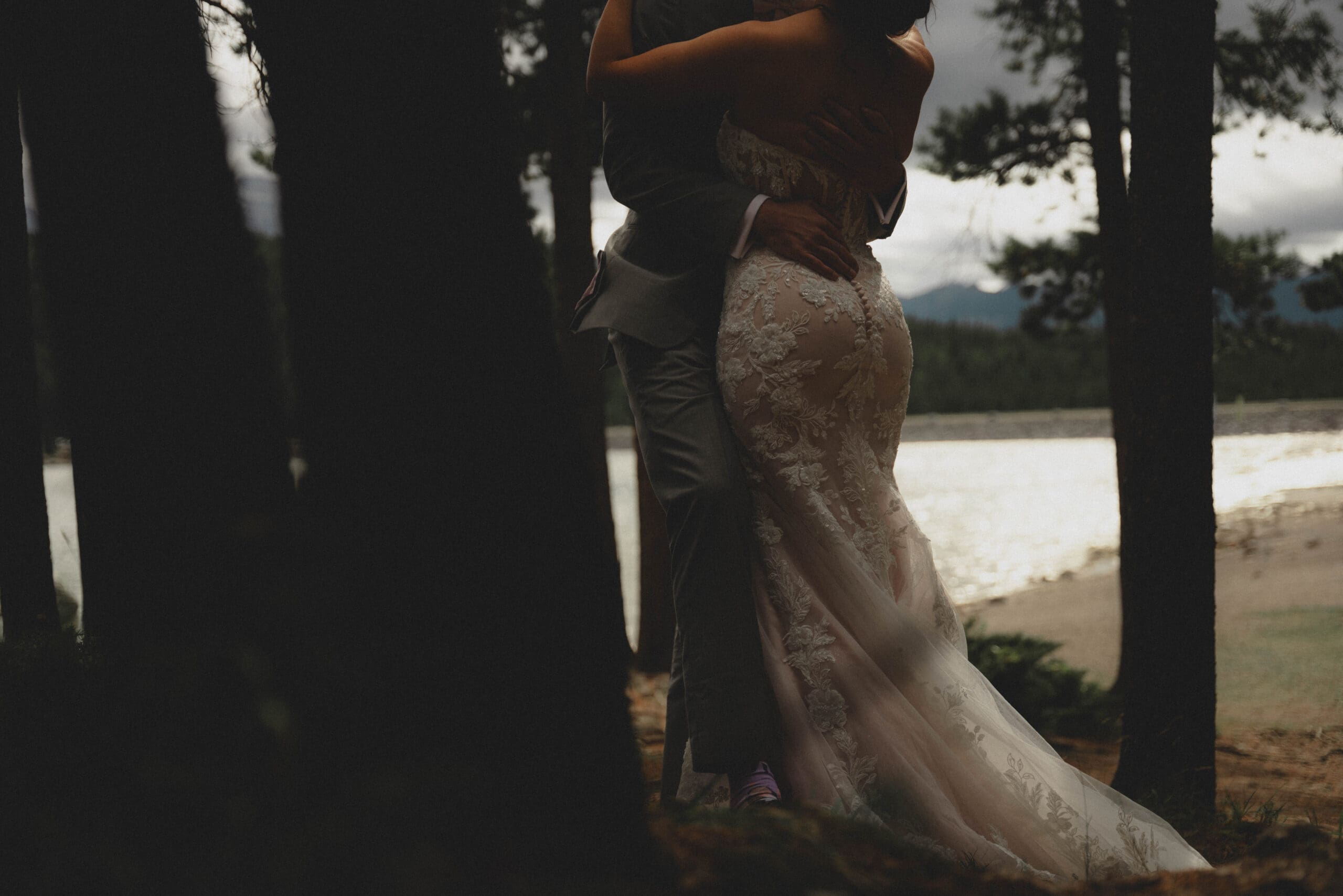 Wedding couple standing in the trees in front of Lake Minnetonka