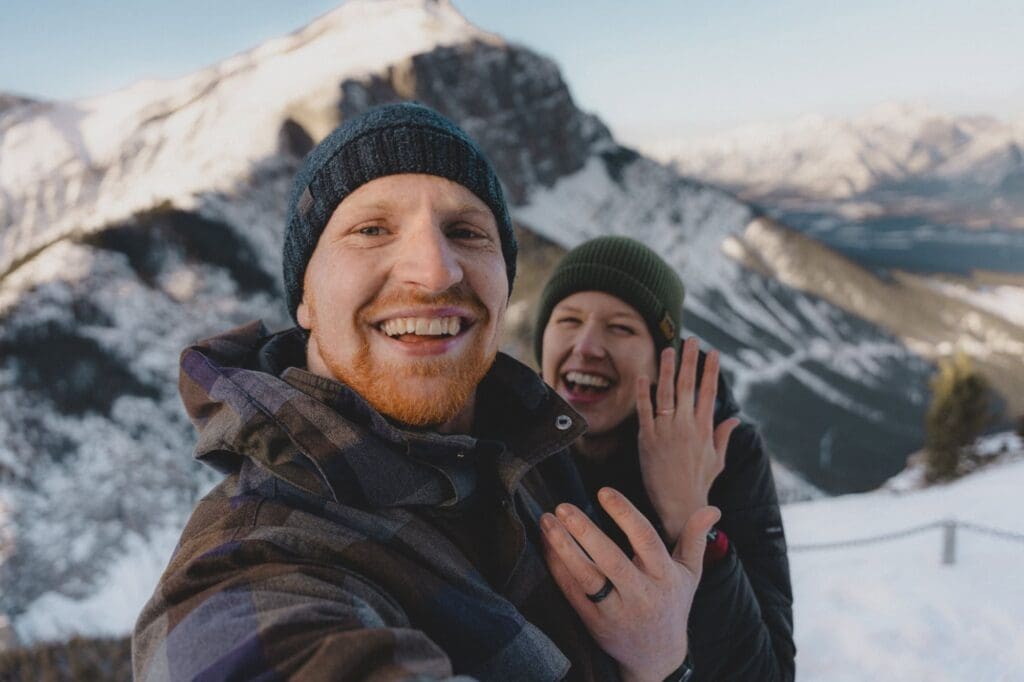 Engaged couples showing off their rings on a mountain
