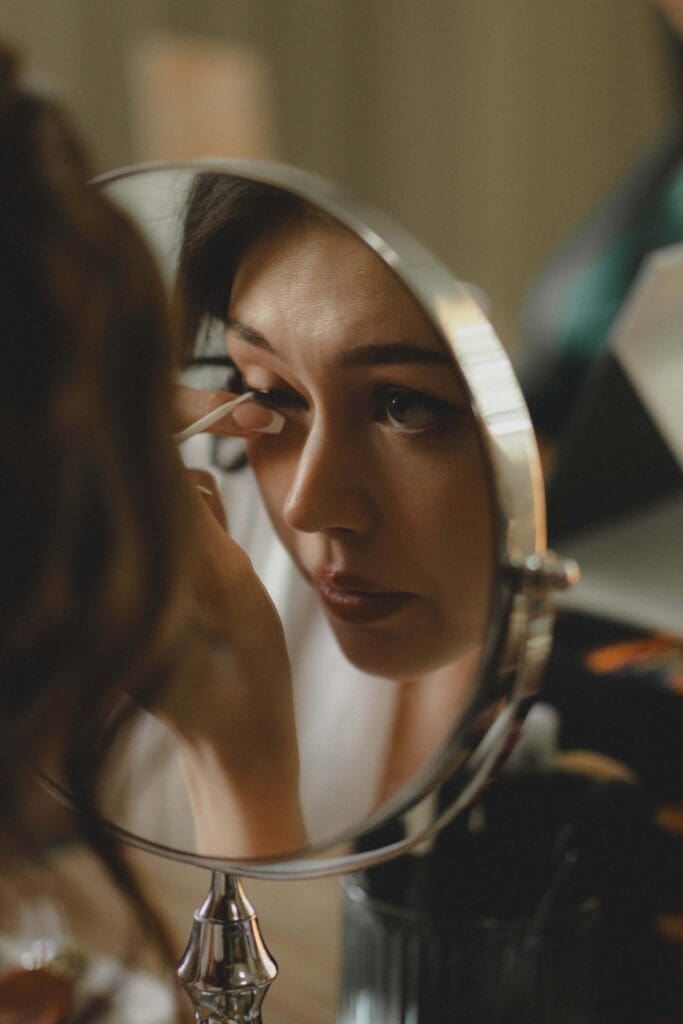 Bride fixing her eyelash in a mirror