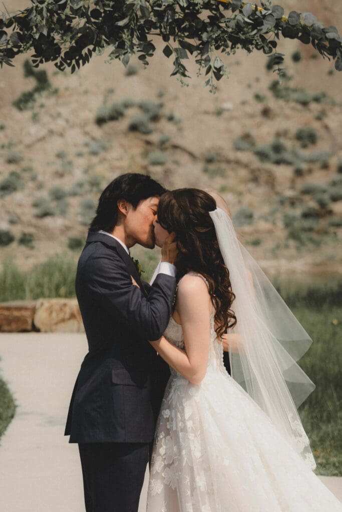 First kiss at a wedding ceremony with the badlands in Drumheller behind them
