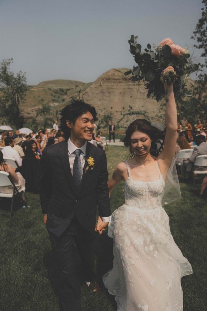 Wedding couple walking down the aisle and laughing at the Badlands Community Facility in Drumheller