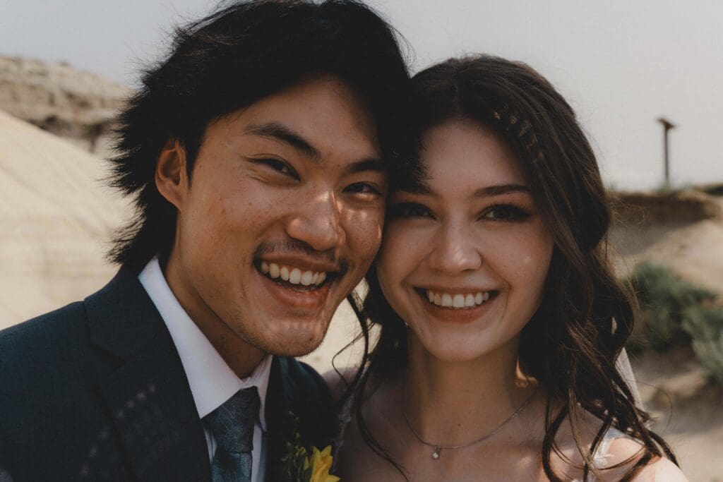 Wedding couple smiling at the camera at the Drumheller Hoodoos