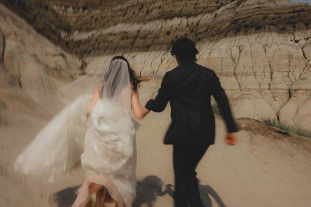 Wedding couple running in the Drumheller Hoodoos
