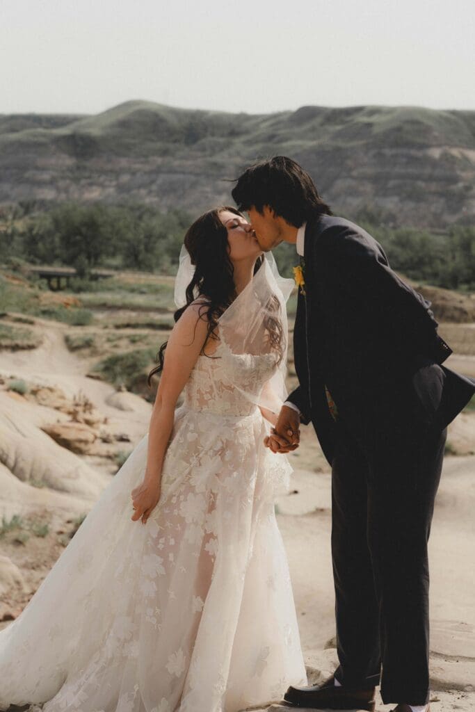Wedding couple kissing in front of the scenery at the Drumheller Hoodoos