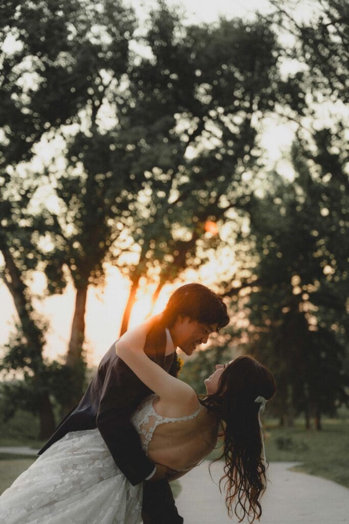 Wedding couple dipping in front of trees and the sunset in Drumheller