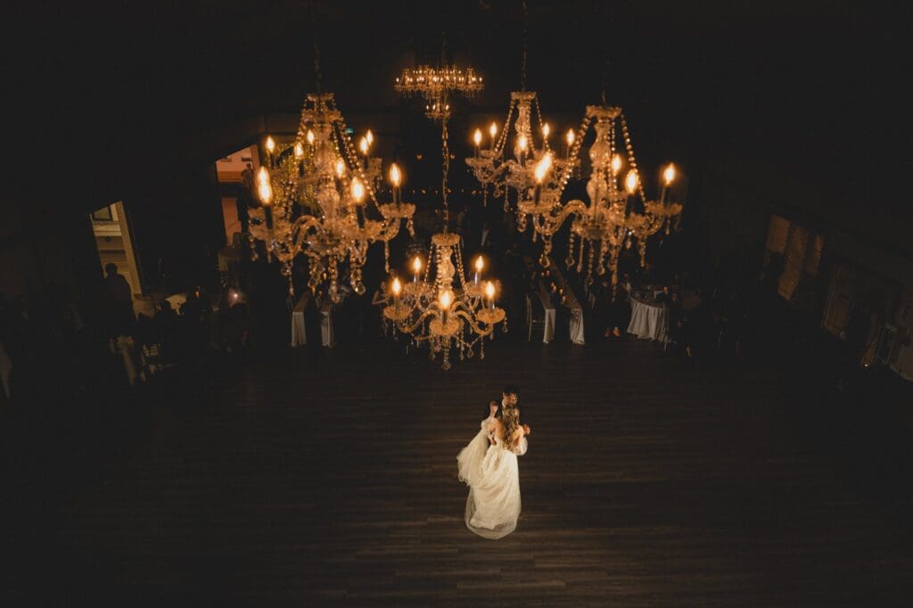 Wedding couple doing their first dance below a chandelier 
