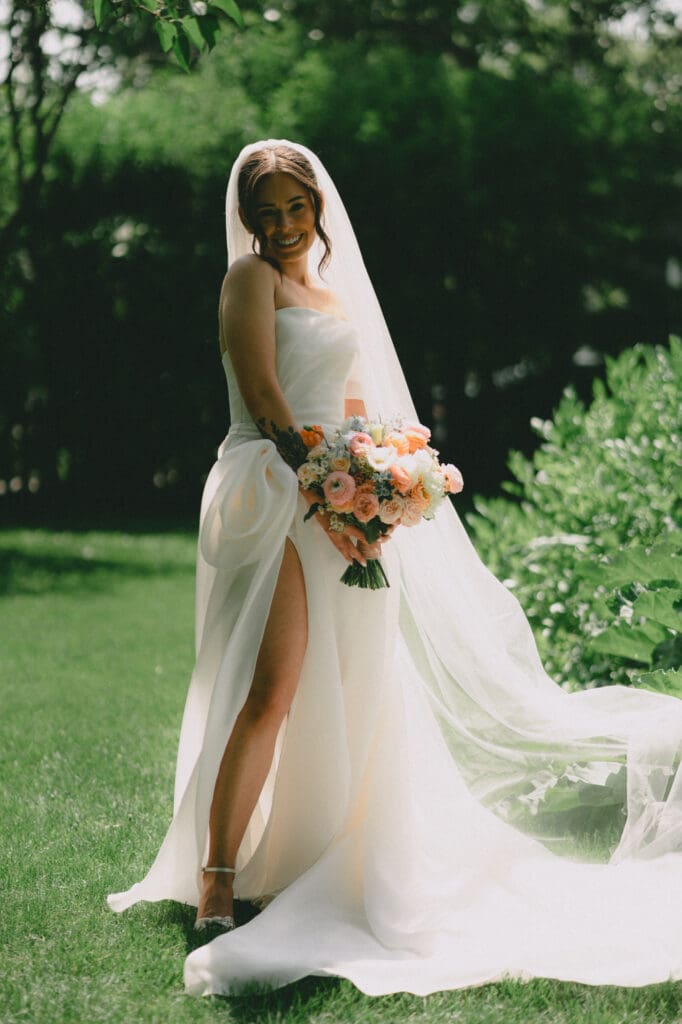 Bride smiling in front of greenery