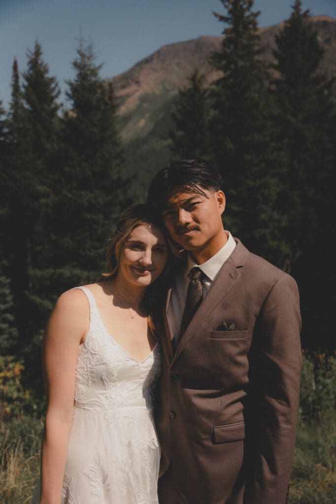 Wedding couple looking at the camera in front of trees at Castle Mountain Resort