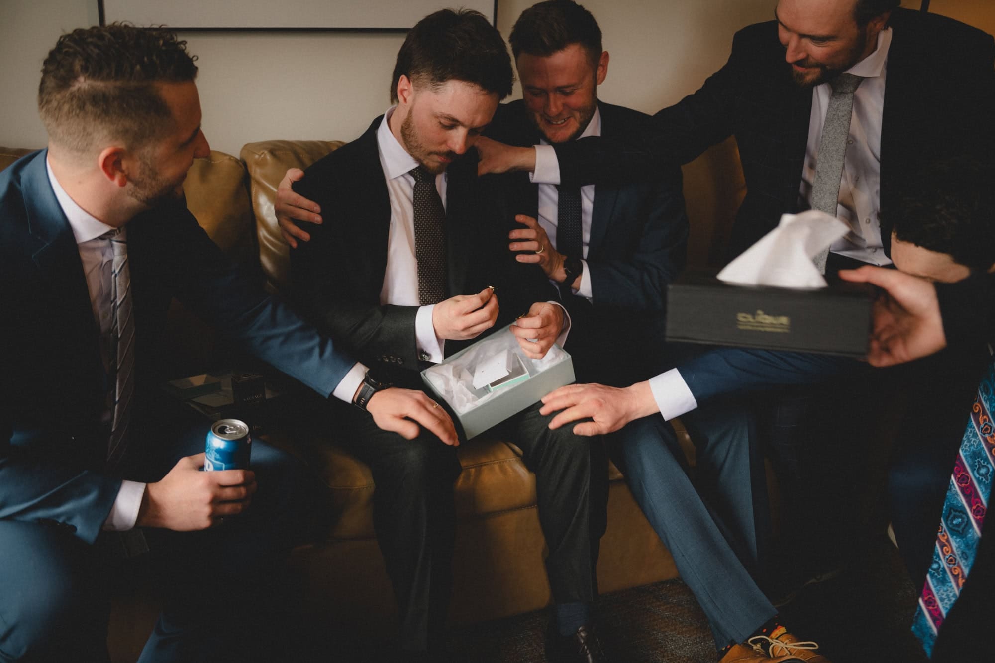 Groomsmen putting their hands supporting groom as he cries